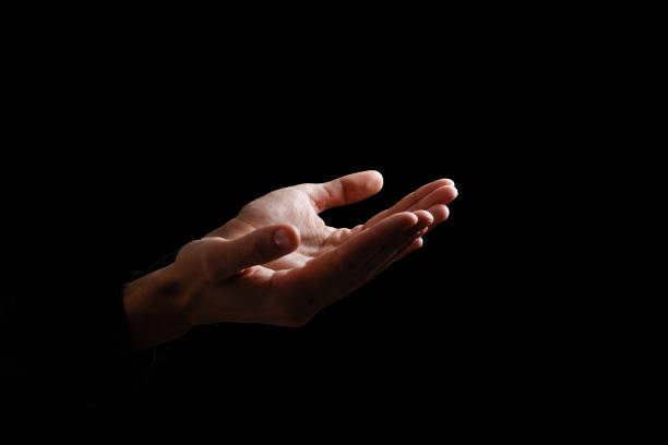 istock Handsome man sit prayer on black background. His hands are praying for God's blessings. 1211747392