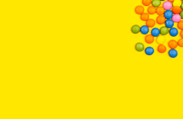 istock Colourful chocolate bean candies on yellow background 1211751003