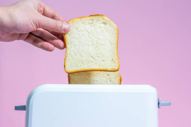 istock making toast a hand holds toast bread on a pink background. free space for text, copy space 1211751843