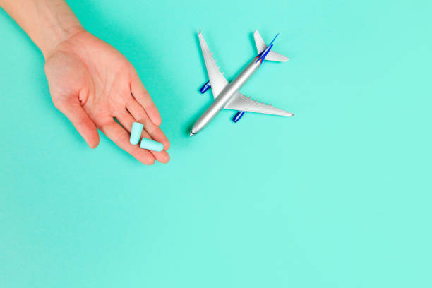 istock Beautiful young woman's hands holding plane and ear plugs  on pastel  background - Image 1211752839