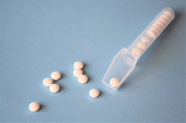 istock white pills scattered on a blue background with a medical dispenser 1211758045