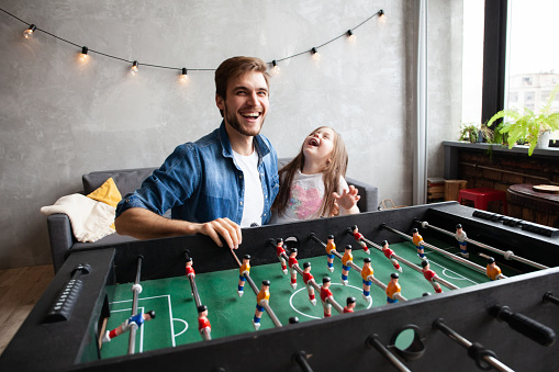 Family holiday and togetherness. Father and daughter playing table football at home