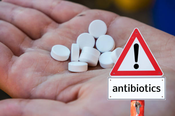 istock Hand holding tablets and warning sign of antibiotics 1211762511