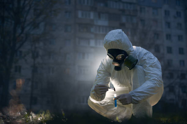 istock Scientist doing research outdoors, wearing white coverall and gas mask 1211762561