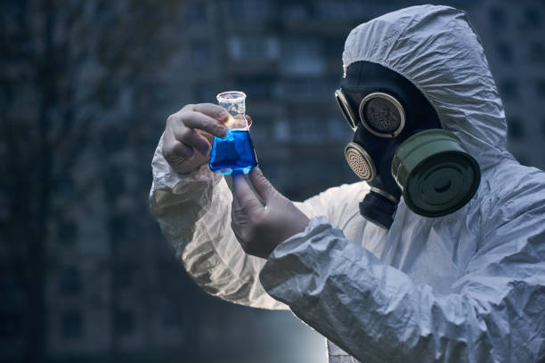 istock Scientist doing research outdoors, wearing white coverall and gas mask 1211762577
