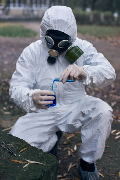 istock Scientist doing research outdoors, wearing white coverall and gas mask 1211762636
