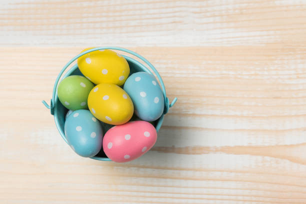 istock Colored bright Easter eggs in a bucket. Light wooden background. Copy space, top view 1211763723