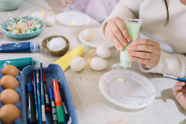 istock Close-up of female hand squeezes paint into a plate for Easter 1211764700