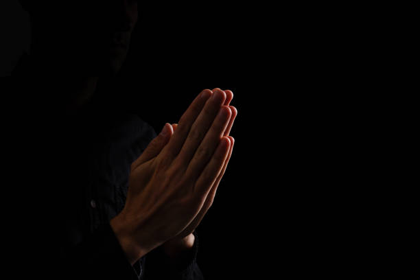 istock Image of praying hands on a black background 1211765223