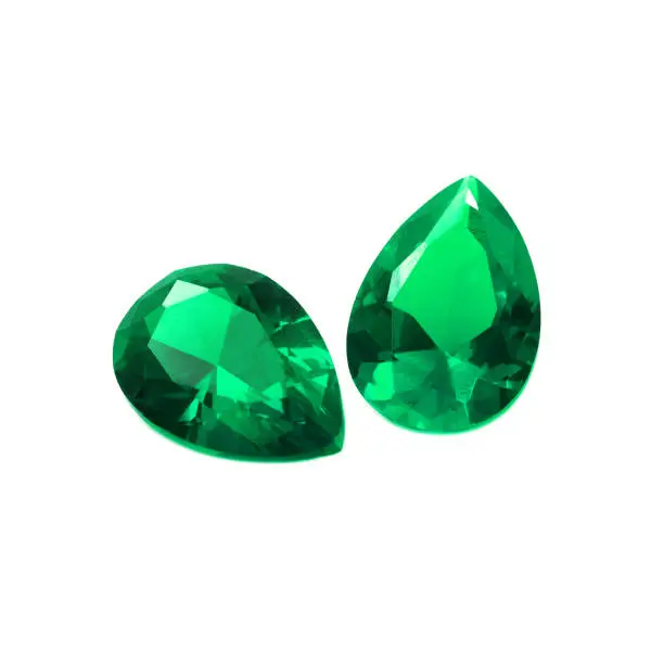 Two pear shaped emeralds on a white background.