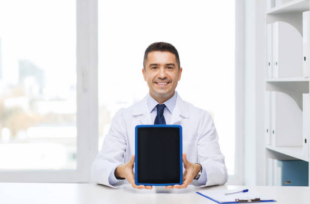 istock smiling male doctor showing tablet pc blank screen 1211768347