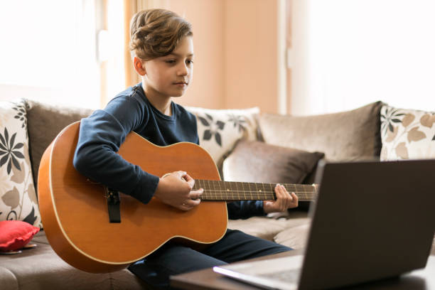 istock Boy having guitar online lesson at home 1211768958