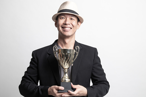Successful Adult Asian man  holding a trophy on white background