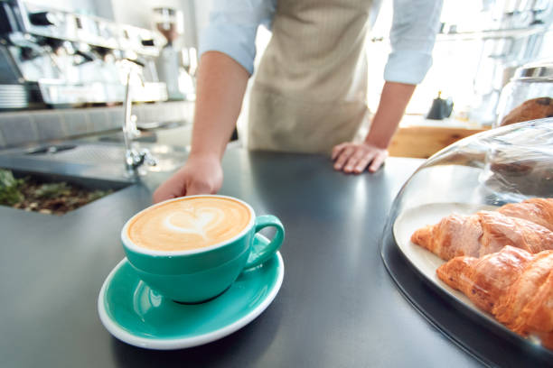 カフェテリアで働く若い大人のバリスタ、コーヒーの近くに立って - barista coffee coffee crop heart shape ストックフォトと画像