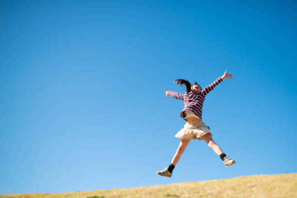 女の子は、腕を開いてジャンプ - 自由 ストックフォトと画像
