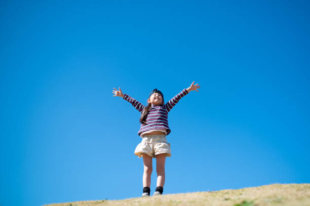istock Girl with open arms on meadow 1211774035