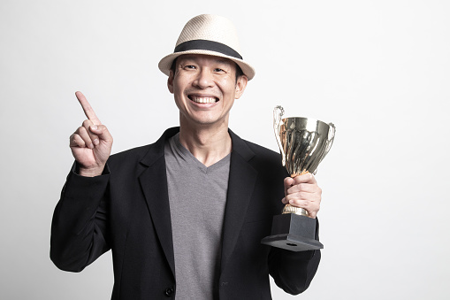 Successful Adult Asian man  holding a trophy point to blank space on white background