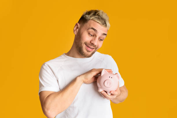 istock Saving concept. Ridiculous guy stroking piggy bank 1211775876