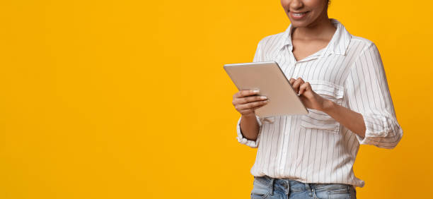 istock Unrecognizable African American Woman Using Digital Tablet, Standing On Yellow Background 1211776008