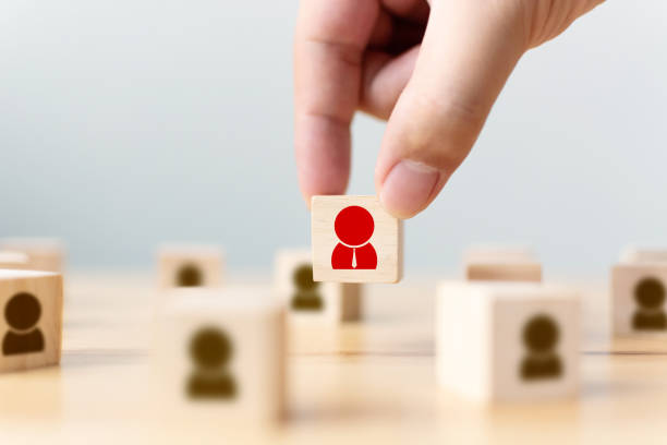 la mano de un hombre de negocios elige un bloque de cubos de madera con personas de icono que destacan entre la multitud. concepto de líder de equipo empresarial exitoso - individuality standing out from the crowd contrasts competition fotografías e imágenes de stock