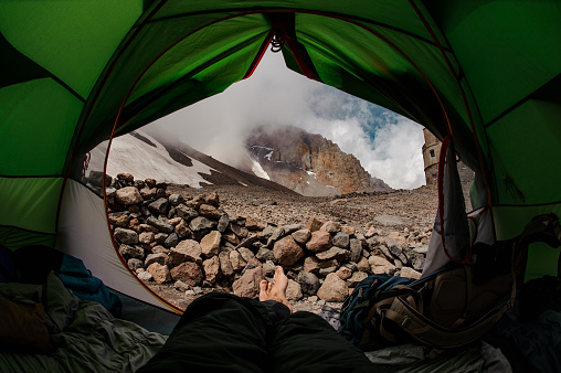 First person view from small green tent at cloudy mountains