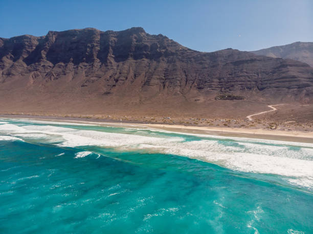 Aerial view of Famara beach with ocean and mountains in Lanzarote, Canary islands Aerial view of Famara beach with ocean and mountains in Lanzarote, Canary islands caleta de famara lanzarote stock pictures, royalty-free photos & images