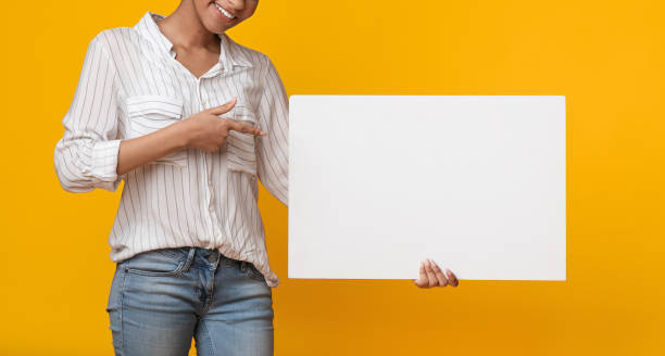 istock Unrecognizable Afro Woman Pointing At White Blank Placard In Her Hands 1211777574