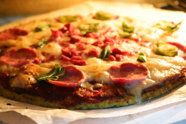 istock Image of cooked homemade pizza baking in oven, cooked on pizza stone for thin and crispy base, pepperoni and fresh basil leaves on top 1211780452