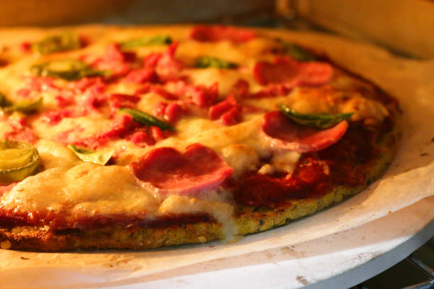 istock Image of cooked homemade pizza baking in oven, cooked on pizza stone for thin and crispy base, pepperoni and fresh basil leaves on top 1211781207