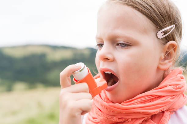 Girl having asthma using asthma inhaler for being healthy