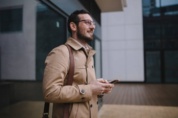 istock Man using mobile phone while walking on street to office 1211781773