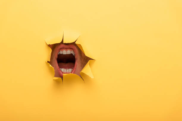 노란색 종이 구멍에서 열린 입의 자른 보기 - human mouth paper screaming hole 뉴스 사진 이미지