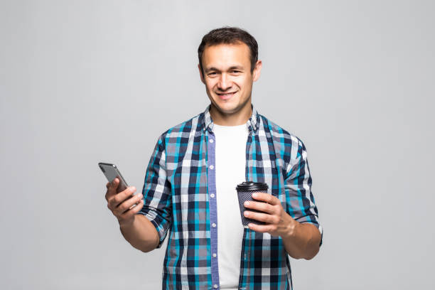 istock Young man look at message he gon on cellphone and drinking coffee, isolated on white background 1211783508