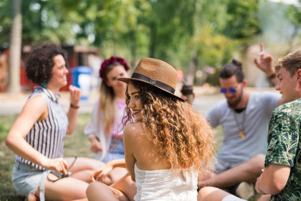 groupe de jeunes amis s’asseyant sur le sol au festival d’été. - music festival park friendship summer photos et images de collection