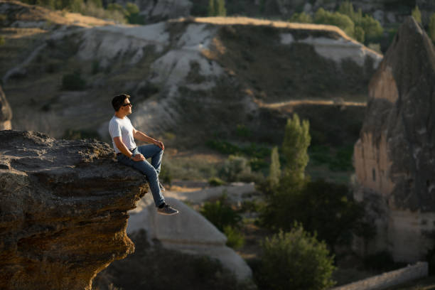 istock a man sitting cliff and looks into the distance. 1211788195
