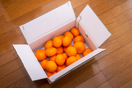There are a lot of Mikan in a cardboard. It's Japanese traditional scene in winter.
