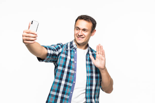 istock Handsome man taking selfie and waving hello to the front camera over white background 1211791205