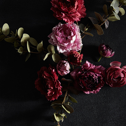 Moody floral concept - flower on dark textured background. Top view, square composition