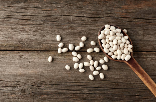 istock white raw whole beans in a brown wooden spoon on the table 1211793621