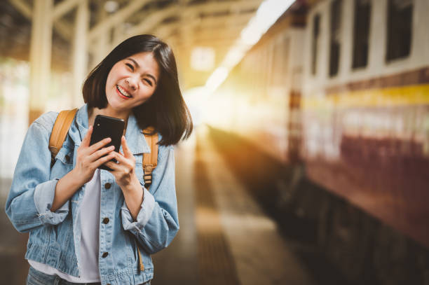 istock woman travel backpacker with smartphone at train station 1211794127