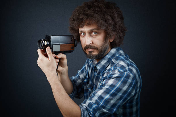 istock Young cinematographer adjusting his old fashioned film camera before shooting a scene with it 1211795675