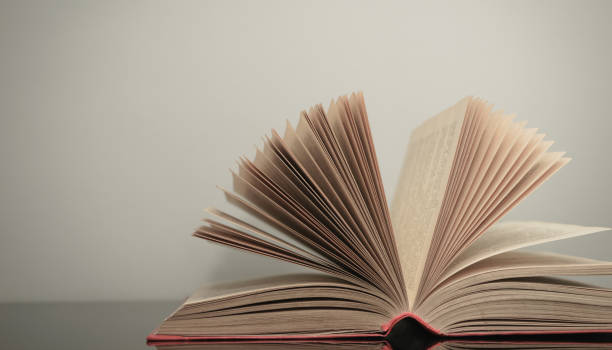 istock Beautiful open book on a gray and glass table background. 1211799989