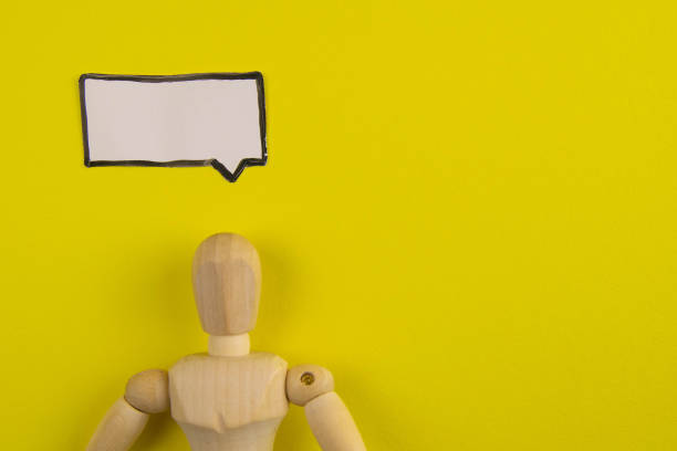 Handcrafted wooden man figure mannequin model dummy doll with blank speech bubble on orange background, objects, nobody