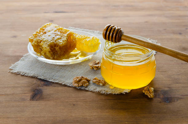 istock Honey slice with honey spoon, walnuts and jar of honey 1211803621