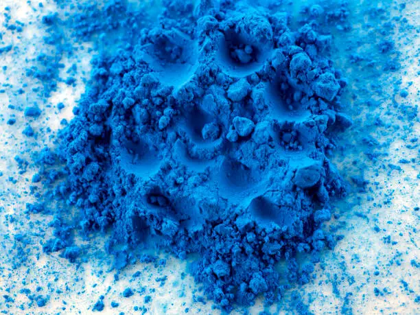 Closeup view of blue pigment. Pigment powder detail. Powders on white background. Abstract background.