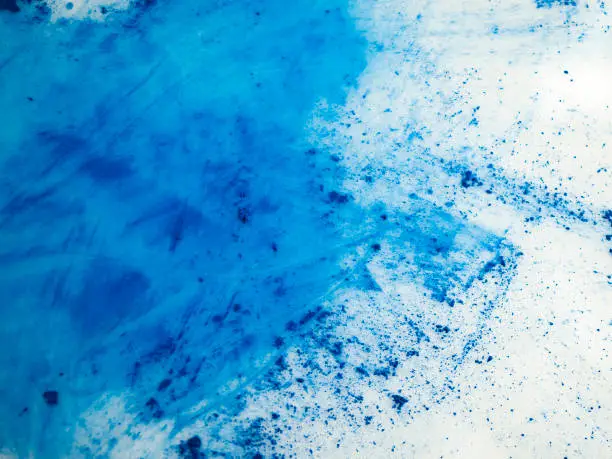 Scattered blue pigment. Abstract background. Blue powder on white background