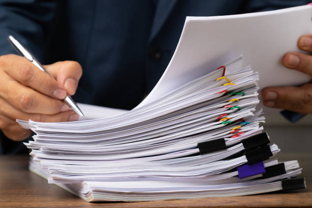 istock Male office workers holding and writing documents on office desk, Stack of business overload paper. 1211804676