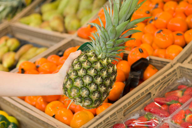 Female hand choosing ananas in the store. Concept of healthy food, bio, vegetarian, diet. Female hand choosing bananas in the store. Concept of healthy food, bio, vegetarian, diet. ananas stock pictures, royalty-free photos & images