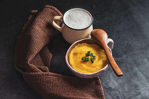 Pumpkin soup with cream and pumpkin seeds on a white background. Shallow focus