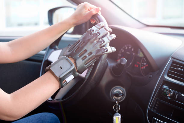 A girl with a prosthetic arm drives a car. The concept of a full life for people with disabilities. Side view, small depth of field. A girl with a prosthetic arm drives a car. The concept of a full life for people with disabilities. Side view, small depth of field. 3d printing hand stock pictures, royalty-free photos & images